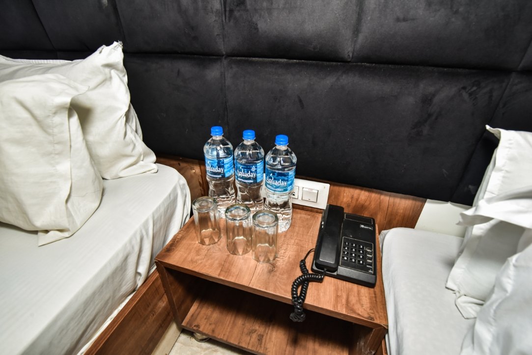 Hotel Woodz room amenities — water bottles, glasses and telephone on bedside table